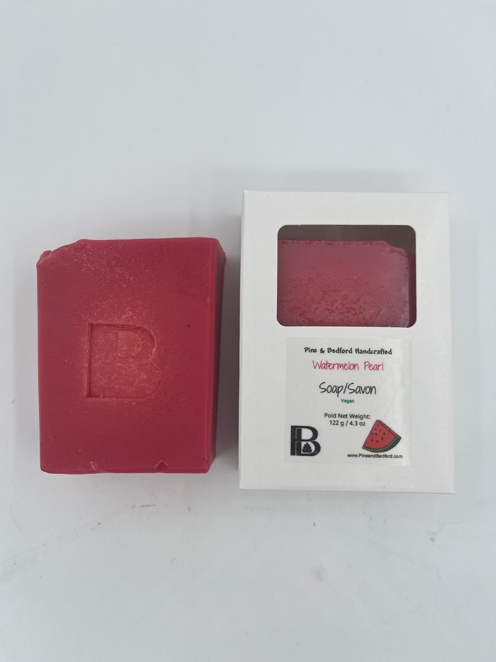 Pine and Bedford's Watermelon Pearl Bar soap, made with Watermelon Juice, Rose Clay, Organic Coconut Oil, Organic Extra Virgin Olive Oil, RSPO Palm Oil, and Castor Oil. The Fragrance is Watermelon Lemonade. A lovely bar to remind you of summer in the dark Canadian Winter. Shown here naked and boxed. 