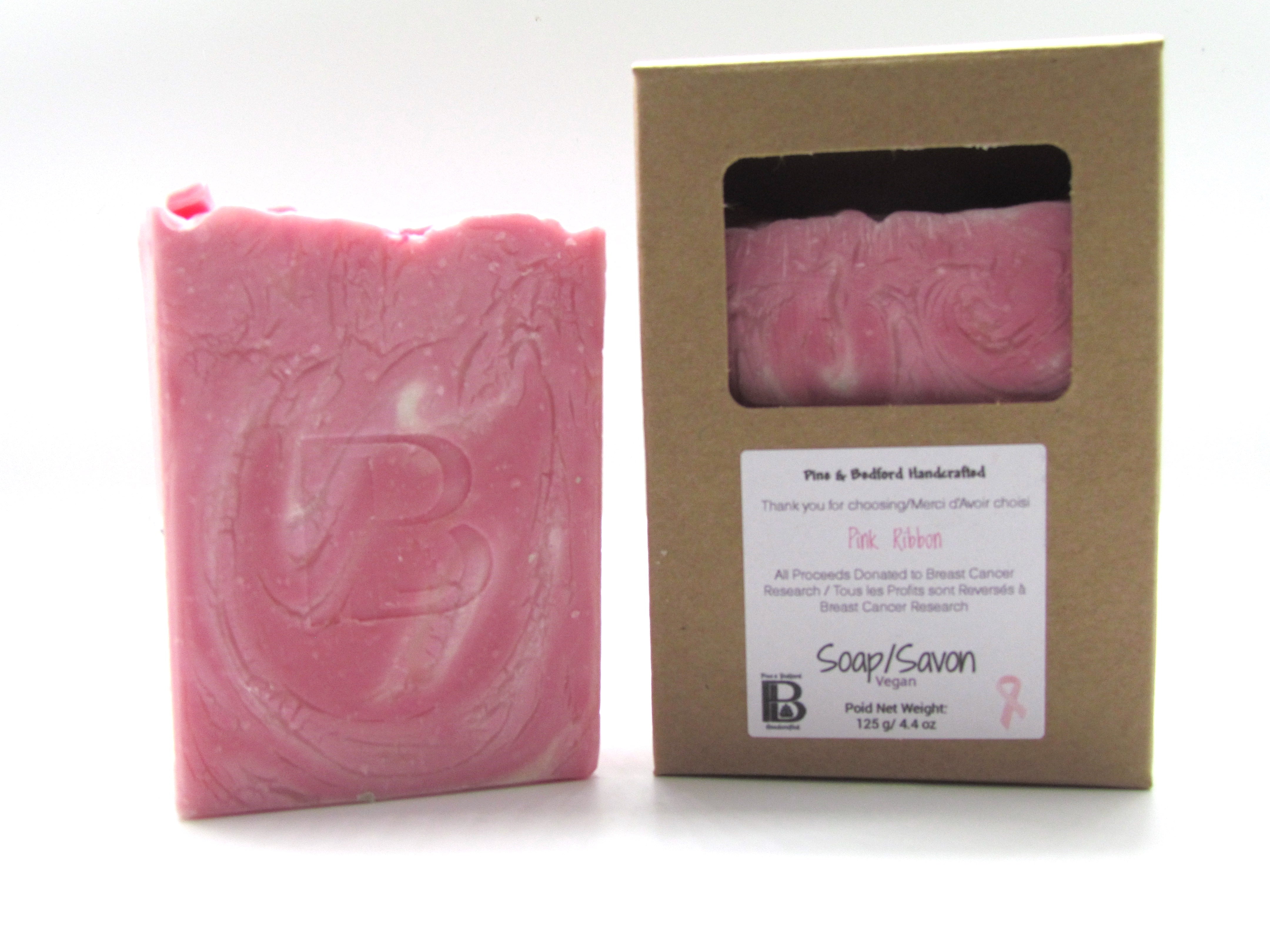 Pine and Bedford's Pink Ribbon soap. A swirl of light and medium pink on a white background with the iconic pink ribbon (made from soap) on the top. Shown here naked and also boxed. All proceeds from this soap will be donated to Breast Cancer Research.