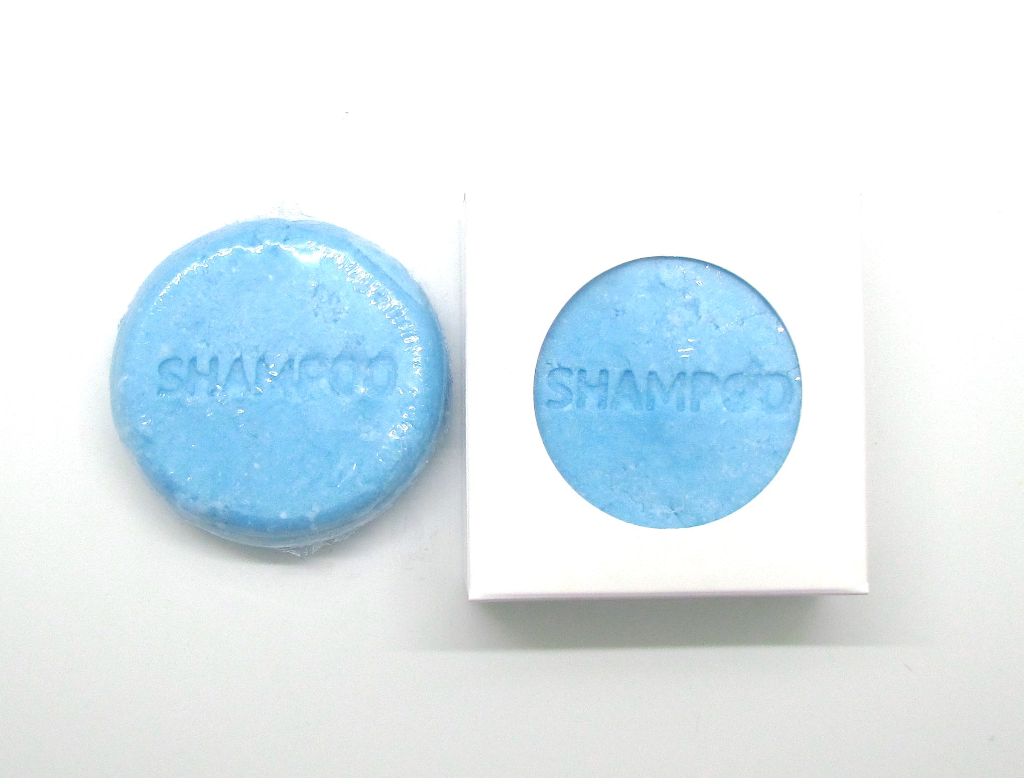 Pine and Bedford's Solid Shampoo Bar for normal hair. A light blue round solid bar with the word 'shampoo' stamped on the top. Available in two fragrances and three sizes. Shown here naked and also boxed.